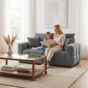 Mother and child reading on a grey 2 seater sofa beside a glass coffee table