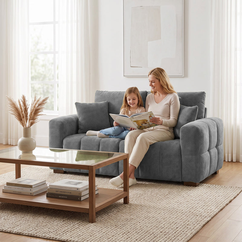 Mother and child reading on a grey 2 seater sofa beside a glass coffee table