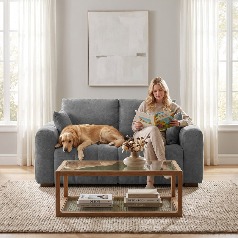 Woman reading with a dog stretched out on a grey 2 seater sofa