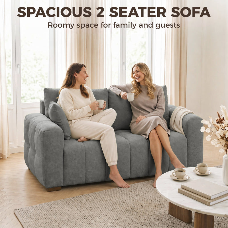 Two women chatting on a grey 2 seater sofa under the heading spacious 2 seater sofa