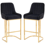 Set of 2 black velvet bar stools with gold legs on a white background