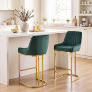 Two dark green velvet bar stools with gold frames at a white kitchen island