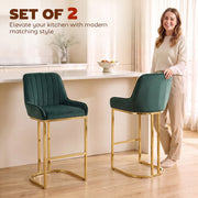 Woman standing beside two dark green velvet bar stools at a kitchen island
