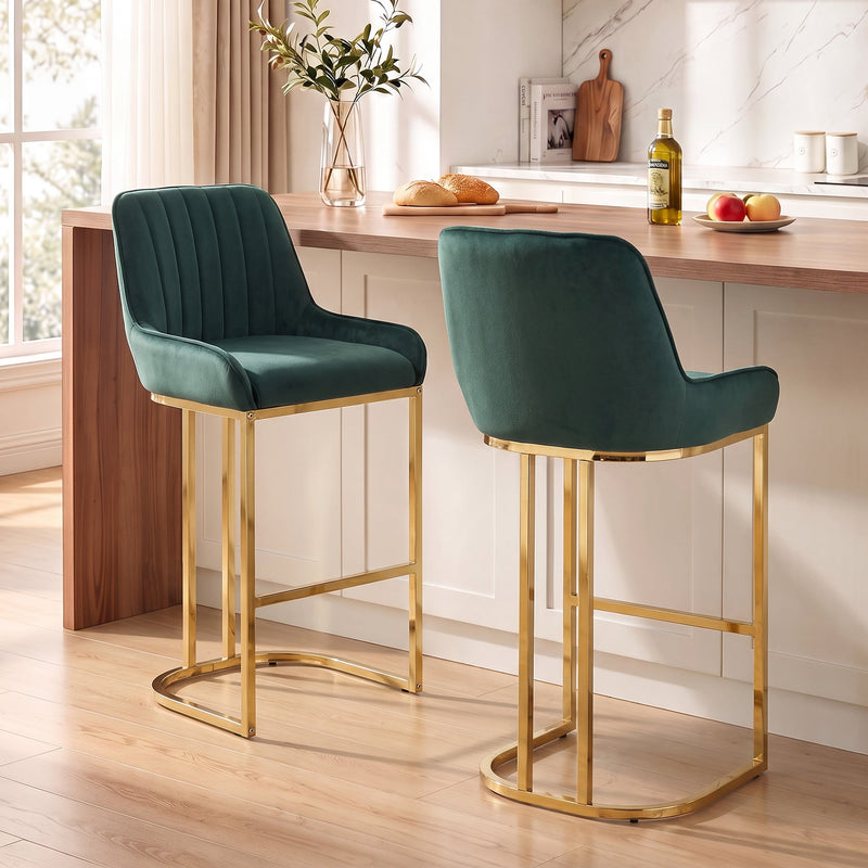 Two dark green velvet bar stools with gold legs at a wooden kitchen counter