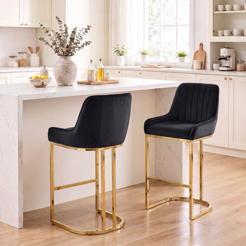 Two black velvet bar stools with gold frames at a white kitchen island