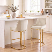 Two cream white velvet bar stools with gold frames at a white kitchen island