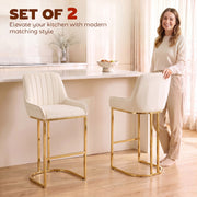 Woman standing beside two cream white velvet bar stools at a kitchen island