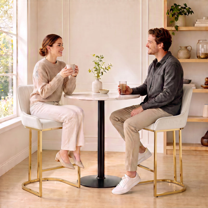 Couple chatting on cream white velvet bar stools at a small round table