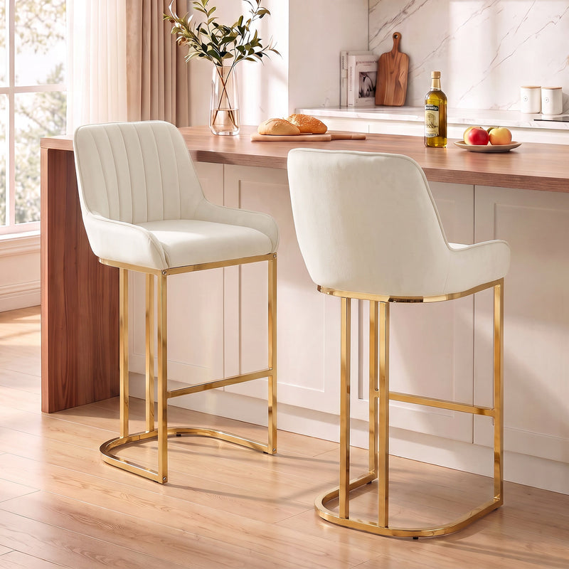 Two cream white velvet bar stools with gold legs at a wooden kitchen counter