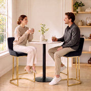 Couple chatting on black velvet bar stools at a small round table