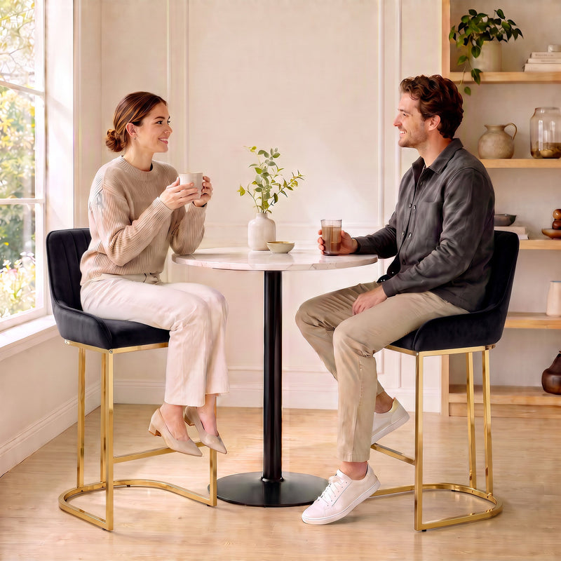 Couple chatting on black velvet bar stools at a small round table