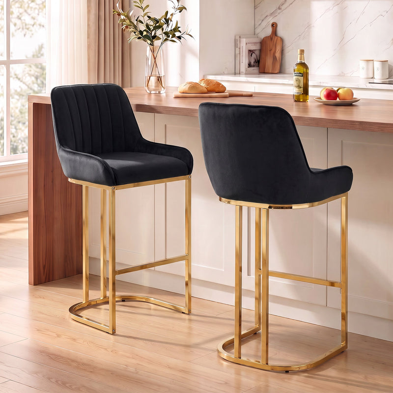 Two black velvet bar stools with gold legs at a wooden kitchen counter