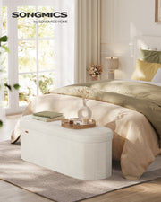 Cream white velvet storage ottoman bench used as an end-of-bed bench in a bedroom
