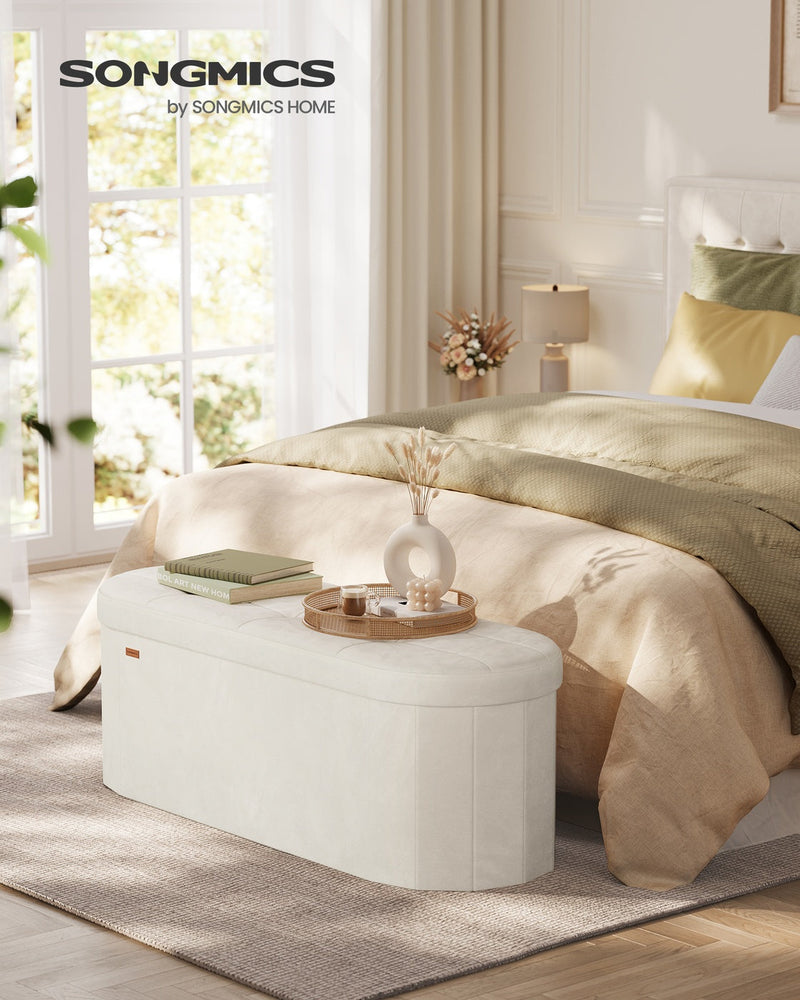Cream white velvet storage ottoman bench used as an end-of-bed bench in a bedroom