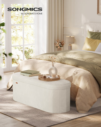 Cream white velvet storage ottoman bench used as an end-of-bed bench in a bedroom