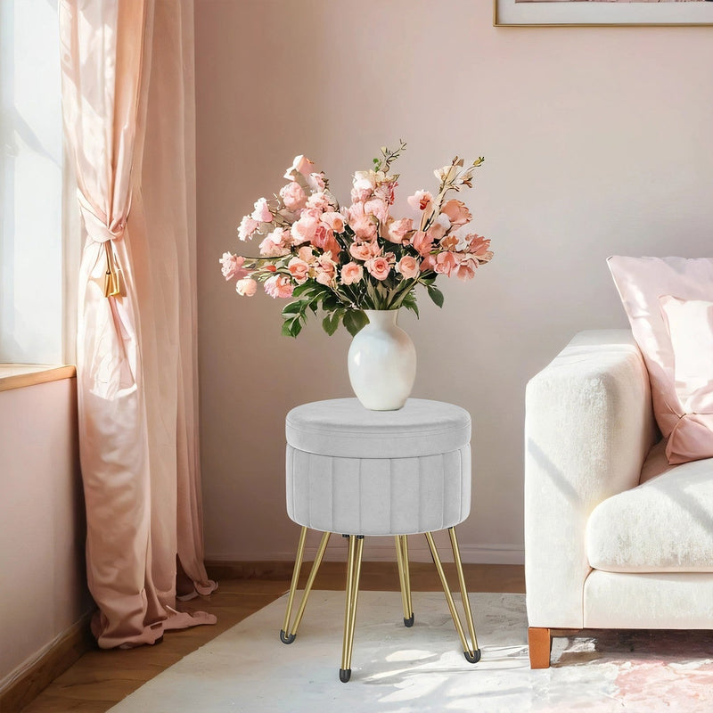 Velvet ottoman used as a side table with a vase of pink flowers in a bedroom corner