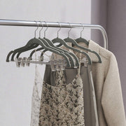 Grey velvet hangers holding dresses and lace clothing on a rail