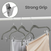 Row of grey velvet hangers holding trousers and skirts neatly on a wardrobe rail