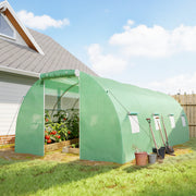 Polytunnel greenhouse in a garden with vegetables growing inside and tools by the door