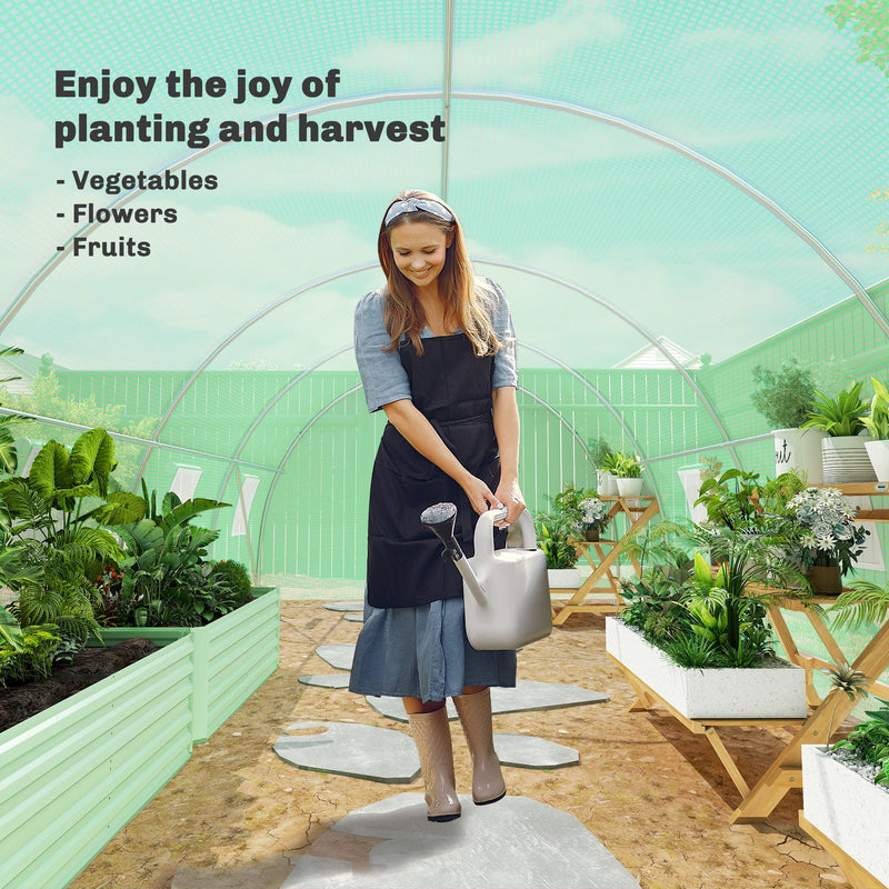Woman watering plants inside the polytunnel beside raised beds of vegetables and flowers