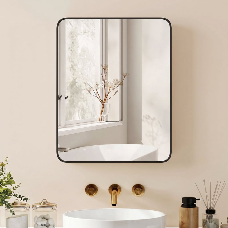 Black mirror cabinet above a white basin with gold taps