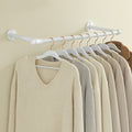 White industrial pipe clothes rail mounted on a wall with knitwear hanging from it