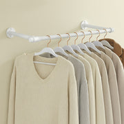 White industrial pipe clothes rail mounted on a wall with knitwear hanging from it
