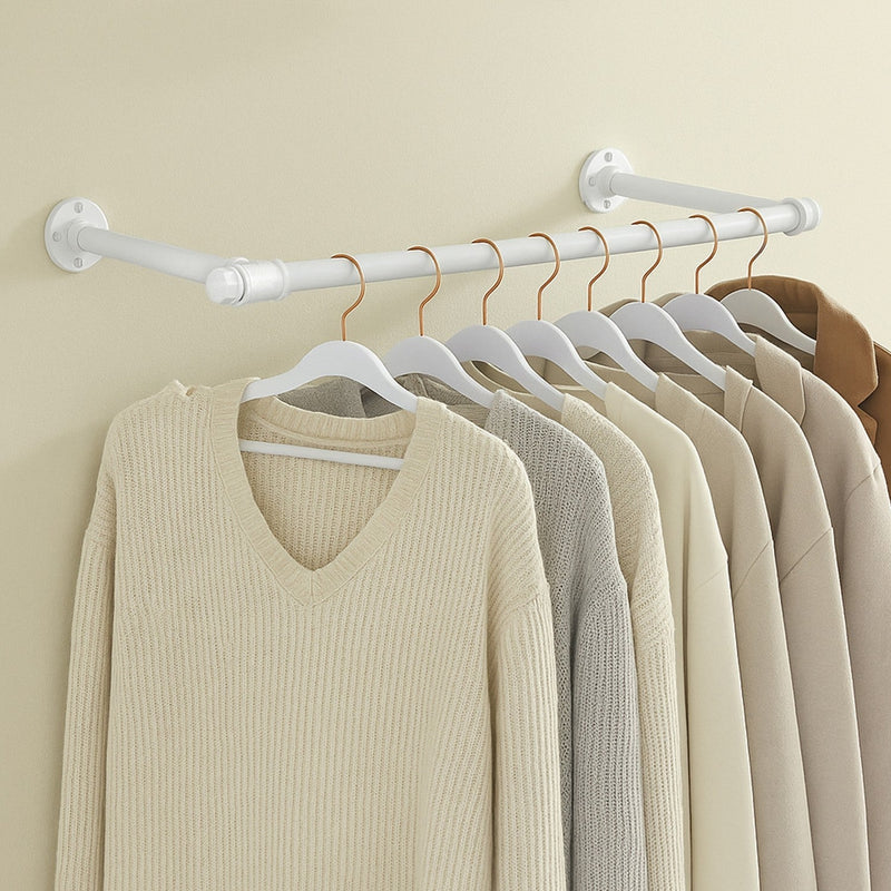 White industrial pipe clothes rail mounted on a wall with knitwear hanging from it