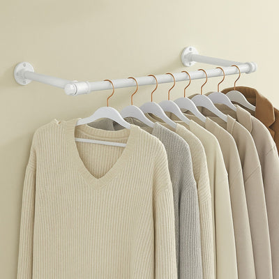 White industrial pipe clothes rail mounted on a wall with knitwear hanging from it