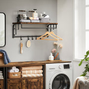 Coat rack fitted in a utility room above a washing machine, holding hangers and brushes