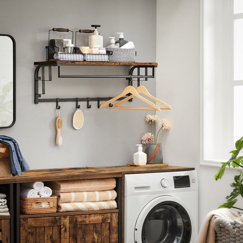 Coat rack fitted in a utility room above a washing machine, holding hangers and brushes