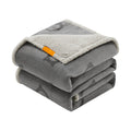 Grey dog blanket folded in a stack showing the patterned flannel face and cream sherpa lining