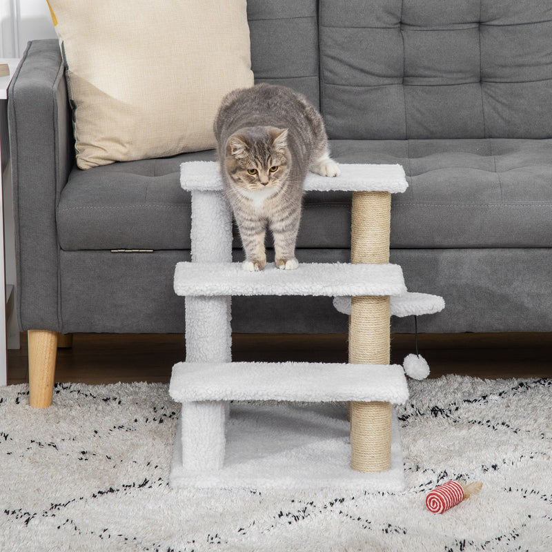 Tabby cat standing on the middle step of the cat stairs in front of a grey sofa