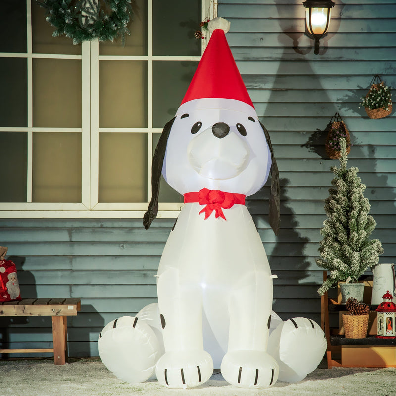 Lit inflatable puppy in a Santa hat in front of a window with a small Christmas tree