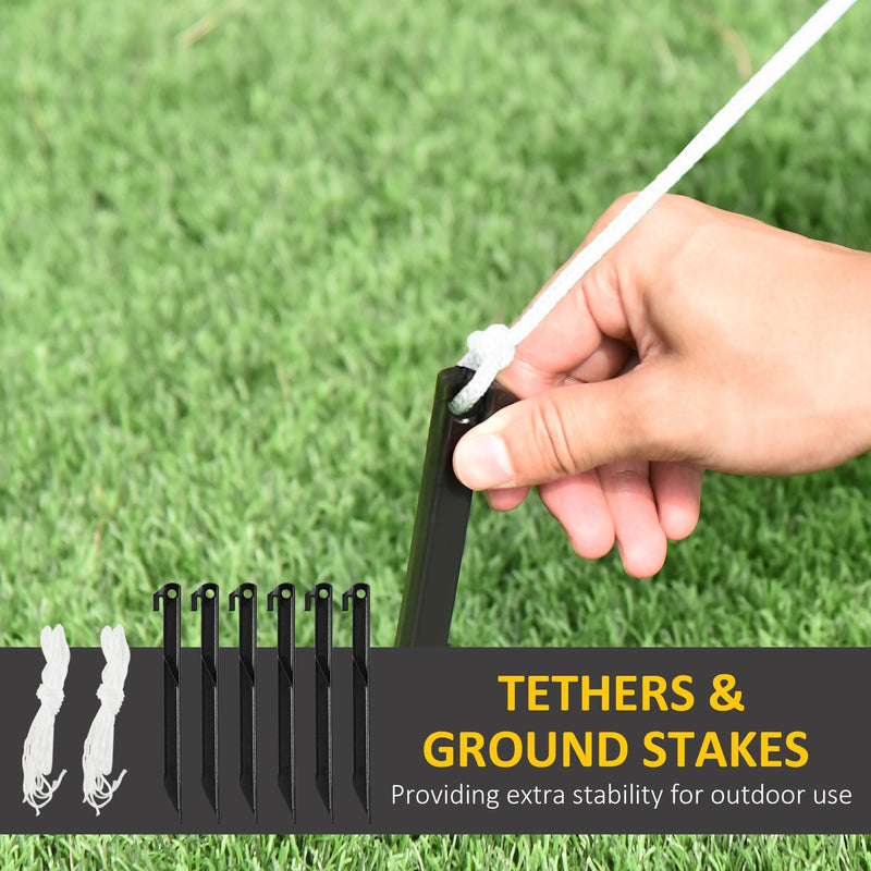 Six ground stakes and two tethers, with a hand attaching a tether to a stake on grass