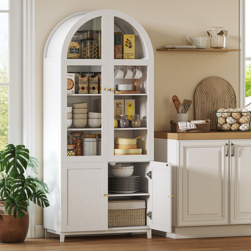 Arched pantry cabinet in a kitchen filled with jars, cups and bowls with a lower door open showing plates