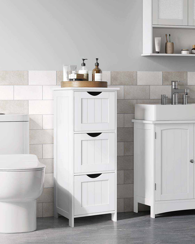 White 3 drawer cabinet standing between a toilet and a basin in a tiled bathroom