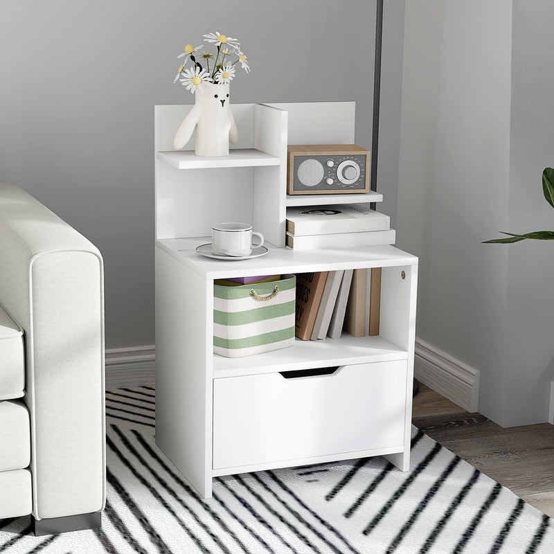 White bedside table next to a sofa holding a radio, books and a storage basket