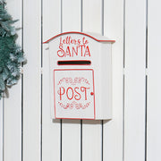 White Santa postbox mounted on a white wooden fence beside a wreath