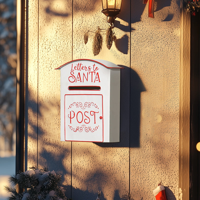 White Santa postbox mounted on a textured wall beside a porch lantern at dusk