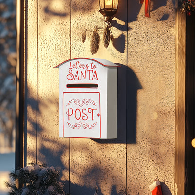 White Santa postbox mounted on a textured wall beside a porch lantern at dusk