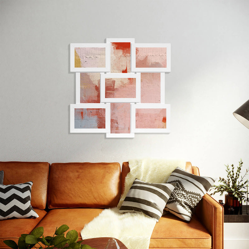 White collage picture frame with abstract pink artwork hung above a tan leather sofa