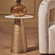 White and gold hammered metal side table styled beside a sofa in a living room