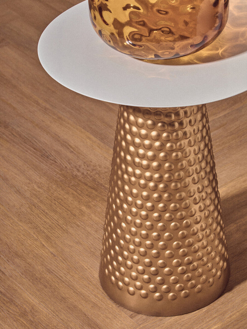 Gold and white side table in a reading corner with an armchair and lamp