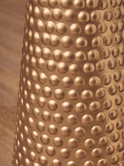 Hammered gold side table shown against a darker wall in a styled interior