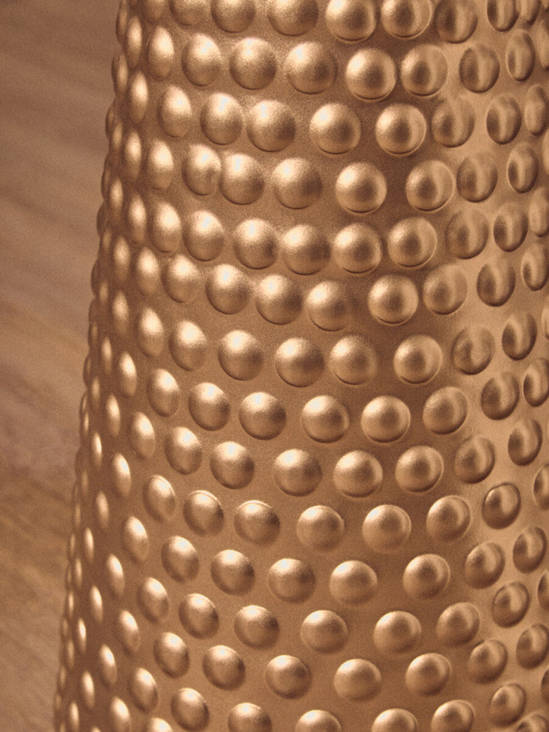 Hammered gold side table shown against a darker wall in a styled interior