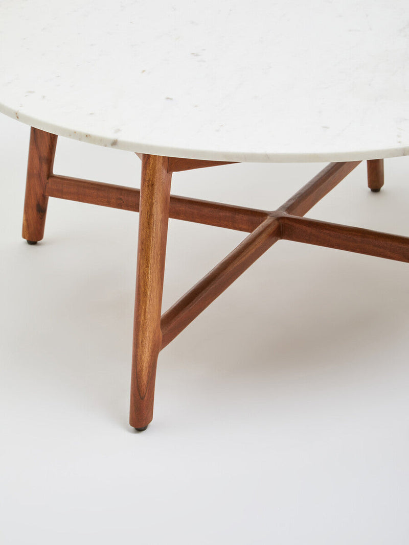 White marble coffee table with acacia wood legs in a decorated interior