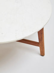 Round marble coffee table viewed at an angle within a living room scheme