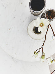Round marble coffee table styled between two armchairs