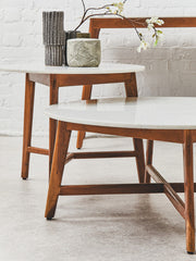 White marble coffee table in a neutral living room beside a floor lamp